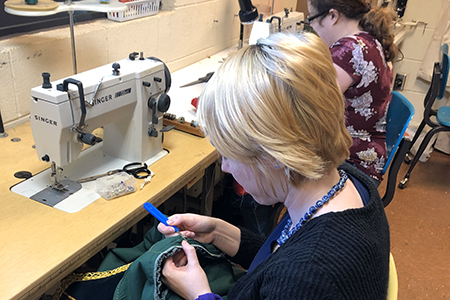 Student sewing a costume for production